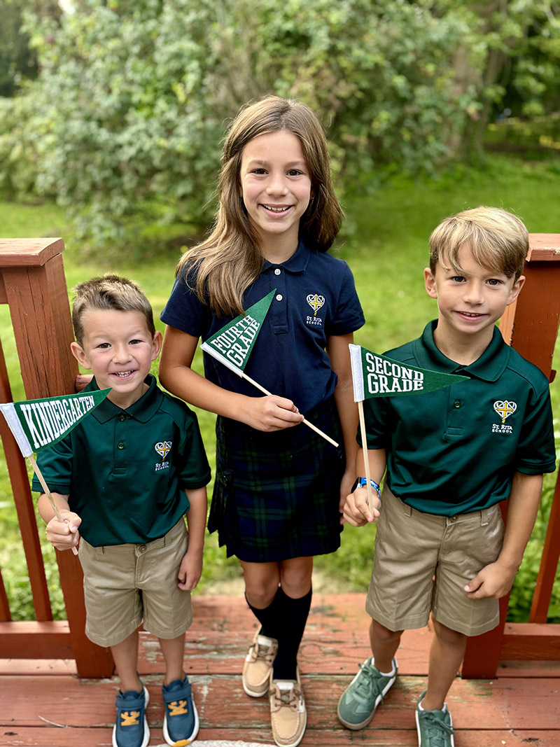 Three happy students in school uniform holding grade flags